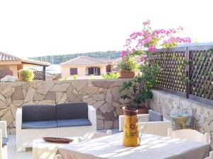 a patio with a table and chairs and a stone wall at Sardegna Top Golfo Di Marinella in Golfo Aranci