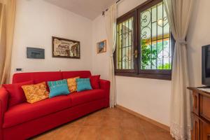 um sofá vermelho numa sala de estar com uma janela em Villa Mallus 4 posti letto em Olìa Speciosa