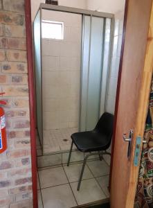 a shower with a black chair in a bathroom at Guesthouse 914 in Sabie