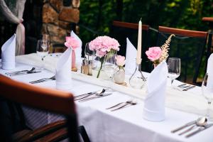 una mesa con flores rosas y servilletas. en KATERAIN hotel, restaurace, wellness, en Opava