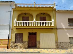 a yellow building with a balcony and a door at Casa MarTa in Chella