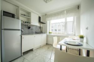 cocina blanca con mesa y nevera en Aparton, en Minsk