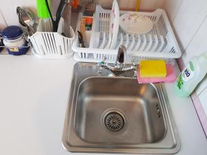 a kitchen sink with a dish drying rack next to it at Апартаменты Нежная орхидея возле реки in Mykolaiv