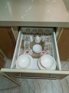 a cabinet filled with white plates and glasses at Al Shadi Apartment Private Tourism in Yanbu