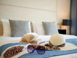 a hat and sunglasses on top of a bed at Athineon Hotel in Rhodes Town