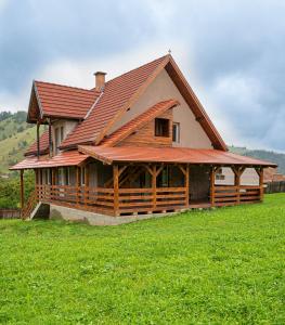 a large house with a red roof on a green field at Anna Guesthouse in Lunca de Sus