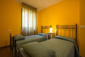 2 letti in una camera da letto con pareti gialle e finestra di Serena Charme View a Mezzolago