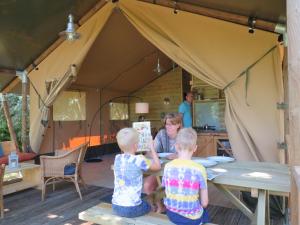 una donna e due bambini seduti a un tavolo in tenda di Domaine Audubert a Saint-Antonin