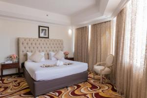 a bedroom with a large white bed and a chair at Ewan Ajman Suites Hotel in Ajman  +18 photos
