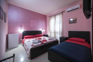 1 dormitorio con 2 camas y paredes rosas en Sun and Beach, en Catona