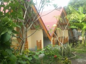 a house with a pink roof in a garden at Tyrrell Cottages & Restaurant in Gili Islands