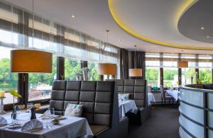 a restaurant with two tables and chairs and windows at Hotel am Wasserfall in Lingen