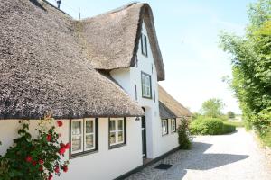 Cottage mit einem Strohdach und einem Weg in der Unterkunft Föhrienhaus in Midlum