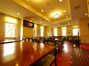 a dining room with tables and chairs and windows at Hotel Route-Inn Honjo Ekiminami in Honjo