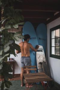 a man is holding a surfboard in a room at Surfescape Fuerteventura in Lajares