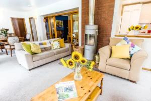 a living room with two couches and a table with sunflowers at Home Comforts in Peaceful 2 Acres in Inverness