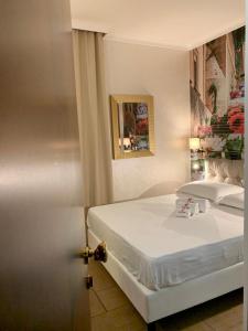 Un dormitorio con una cama blanca y una pintura en la pared en Hotel Flora, en Noto