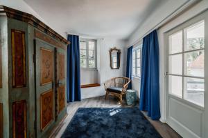 um quarto com cortinas azuis, uma cadeira e uma janela em Smile Apartments zum Goldenen Strauß em Dürnstein