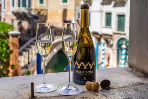een fles wijn en twee glazen op een tafel bij Hotel Donà Palace in Venetië