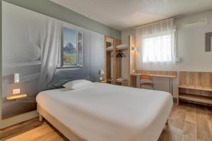 - une chambre avec un grand lit blanc et une fenêtre dans l'établissement B&B HOTEL Pau Lescar, à Lescar