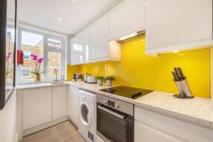 a kitchen with white cabinets and a washer and dryer at Marylebone - Wyndham Street by Viridian Apartments in London