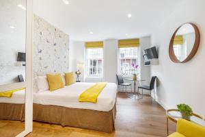 - une chambre d'hôtel avec un lit et un miroir dans l'établissement Marylebone - Wyndham Street by Viridian Apartments, à Londres