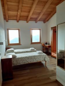 a bedroom with two beds and a desk and two windows at Staulir Affittacamere in Meduno