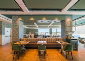 a restaurant with wooden tables and green chairs at Catalonia Donosti in Donostia-San Sebastián