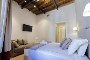 a white bedroom with a bed and a couch at Monti Panisperna suites in Rome