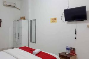a bedroom with a bed and a tv on the wall at RedDoorz near Lampung Walk 2 in Tanjungkarang
