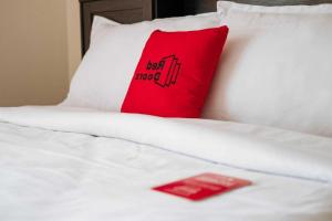 a red pillow sitting on top of a white bed at RedDoorz near Lampung Walk 2 in Tanjungkarang