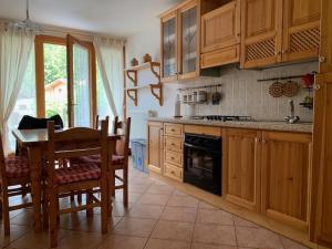 eine Küche mit Holzschränken, einem Tisch und einem Esszimmer in der Unterkunft CHALET ARIANNA in Molveno