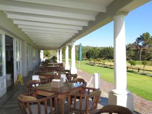a porch with tables and chairs on a house at Goose Valley Retreat with Sea Views in Plettenberg Bay