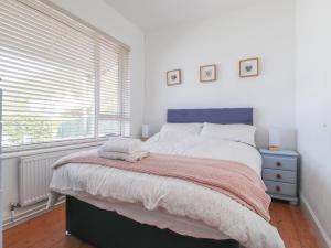 a bedroom with a bed with a blue headboard and a window at Delyn Aur in Cardigan