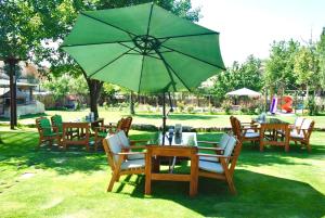 a group of tables and chairs with a green umbrella at Melis Cave Hotel in Urgup
