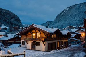 a log cabin in the snow with mountains at Chalet Melodie in Morzine