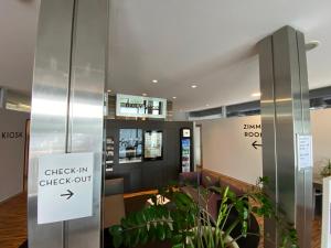 um lobby com um sinal de check-in check-out e plantas em Hotel Arte Spreitenbach em Spreitenbach