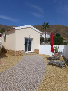 una casa con sombrilla roja y silla en Los Torres Casa Lindsay, en Arboleas