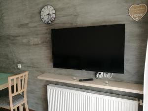 telewizor z płaskim ekranem na ścianie z zegarem w obiekcie Wrzosowy Resort Pogorzelica Apartament PERŁOWY Sea&Forest w Pogorzelicy +15 zdjęć