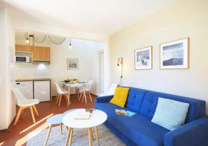 a living room with a blue couch and a kitchen at Résidence Néméa Les Carrats - Port Leucate in Port Leucate