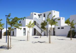 a white building with trees in front of it at Résidence Néméa Les Carrats - Port Leucate in Port Leucate