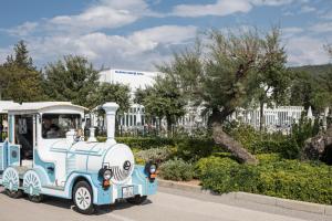a small blue and white train driving down a street at Falkensteiner Hotel Park Punat in Punat