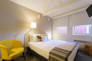 ポルトにあるStay in Apartments Ribeira 24のベッドと黄色い椅子が備わるホテルルームです。