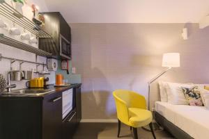 um pequeno quarto com uma cama e uma cadeira amarela em Stay in Apartments Ribeira 24 no Porto