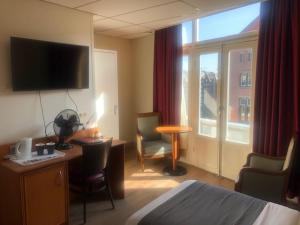 a hotel room with a bed and a desk and a large window at Delta Hotel City Center in Amsterdam