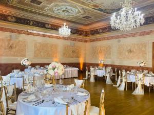 un salón de banquetes con mesas y sillas blancas y lámparas de araña en Hotel Jelen en Hlohovec