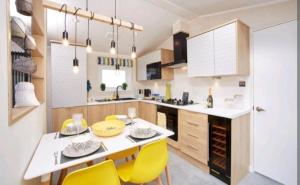 a kitchen with a dining table and yellow chairs at View point lodge in Newton on the Moor