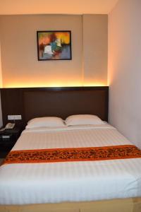 1 dormitorio con 1 cama grande con colcha blanca en Sunrise Hotel en Petaling Jaya