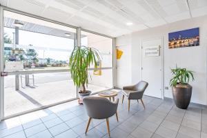 een wachtkamer met twee stoelen en een plant bij B&B HOTEL Bordeaux Sud Mios in Mios
