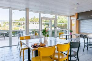 una sala da pranzo con tavoli, sedie e finestre di B&B HOTEL Bordeaux Sud Mios a Mios